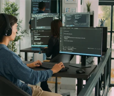 An Impimpi Tech software engineer wearing headphones and writing code on a desktop computer in an office.